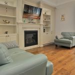 Custom millwork built-ins in cream frame a gas fireplace with marble surround in the finished family room