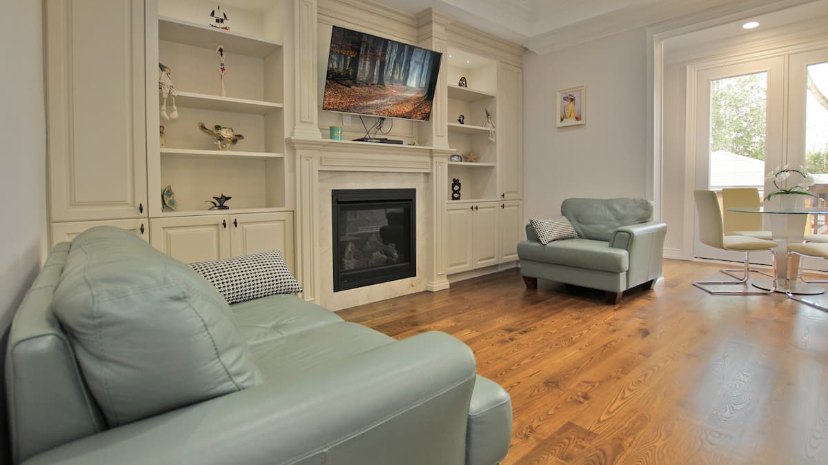 Custom millwork built-ins in cream frame a gas fireplace with marble surround in the finished family room