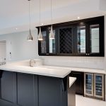 Espresso wet bar millwork with glass-front uppers, lattice wine rack, white quartz counters and dual-zone wine fridge
