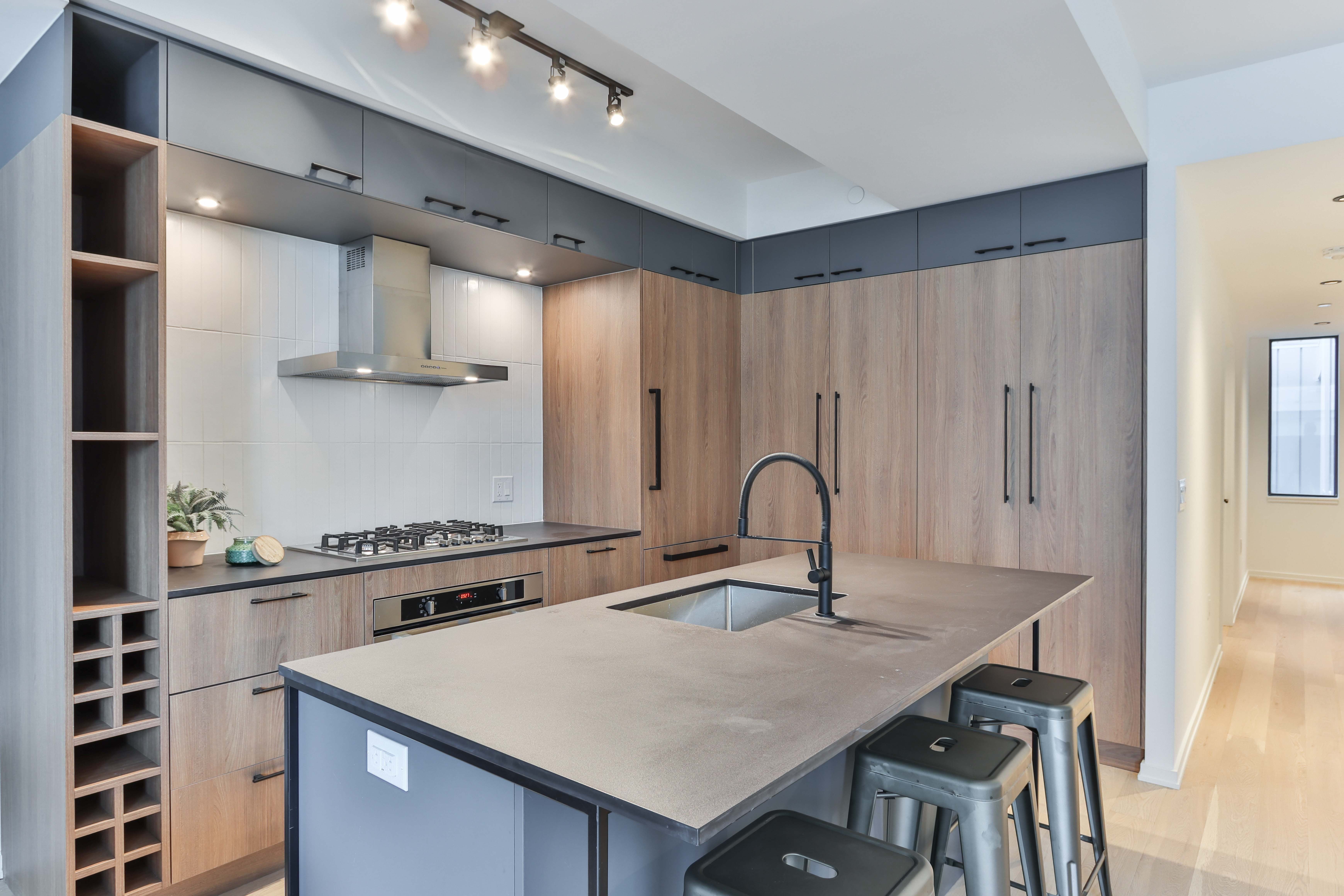 Wood-grain slab cabinets with navy uppers and a concrete-look island counter in a completed kitchen renovation
