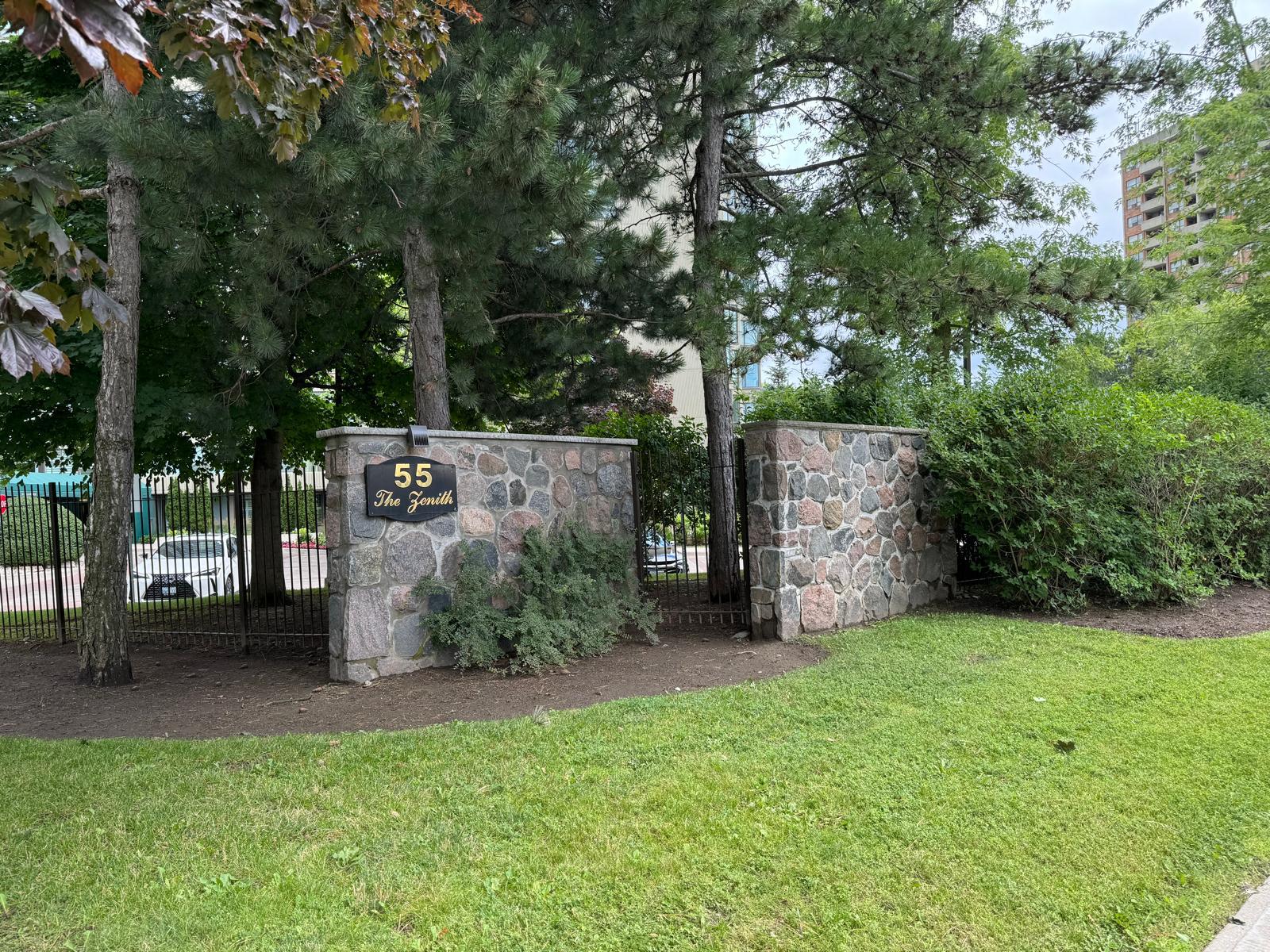 Completed fieldstone entrance wall with 55 The Zenith plaque and wrought-iron fencing at a North York condominium