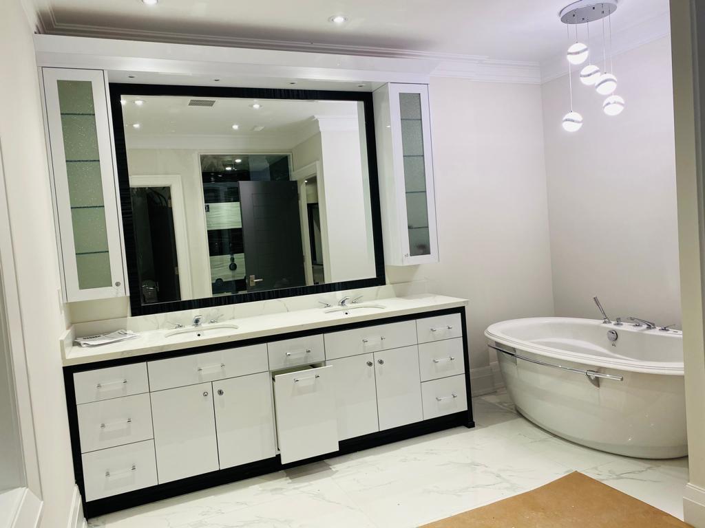 Freestanding tub with chrome filler below a globe chandelier in a master bath, floor protection paper still down