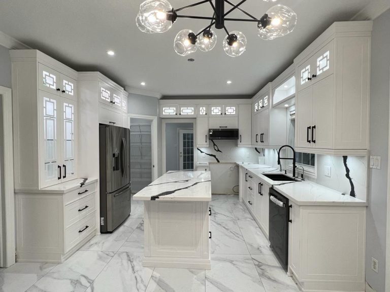 White kitchen renovation in progress: lit fretwork glass uppers, black-veined quartz island, unfinished range opening