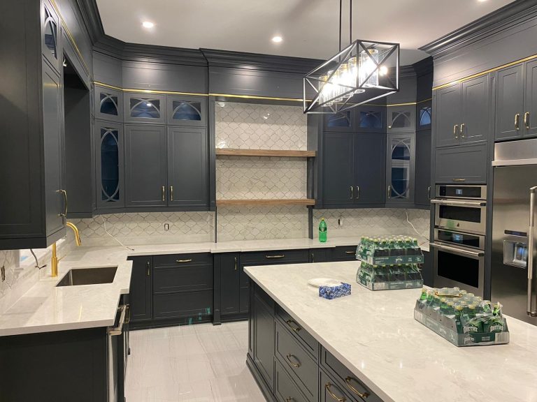 Charcoal cabinetry with gold trim band and fretwork glass uppers, twin gold-faucet sink stations and a quartz-top island
